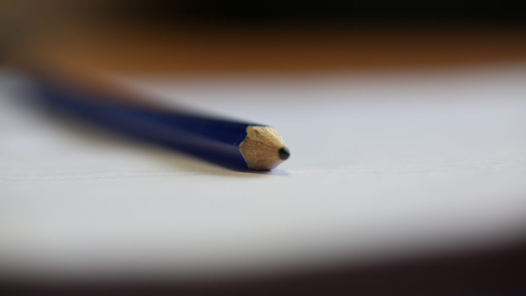 A pencil laying on a piece of paper. Very shallow depth of focus.