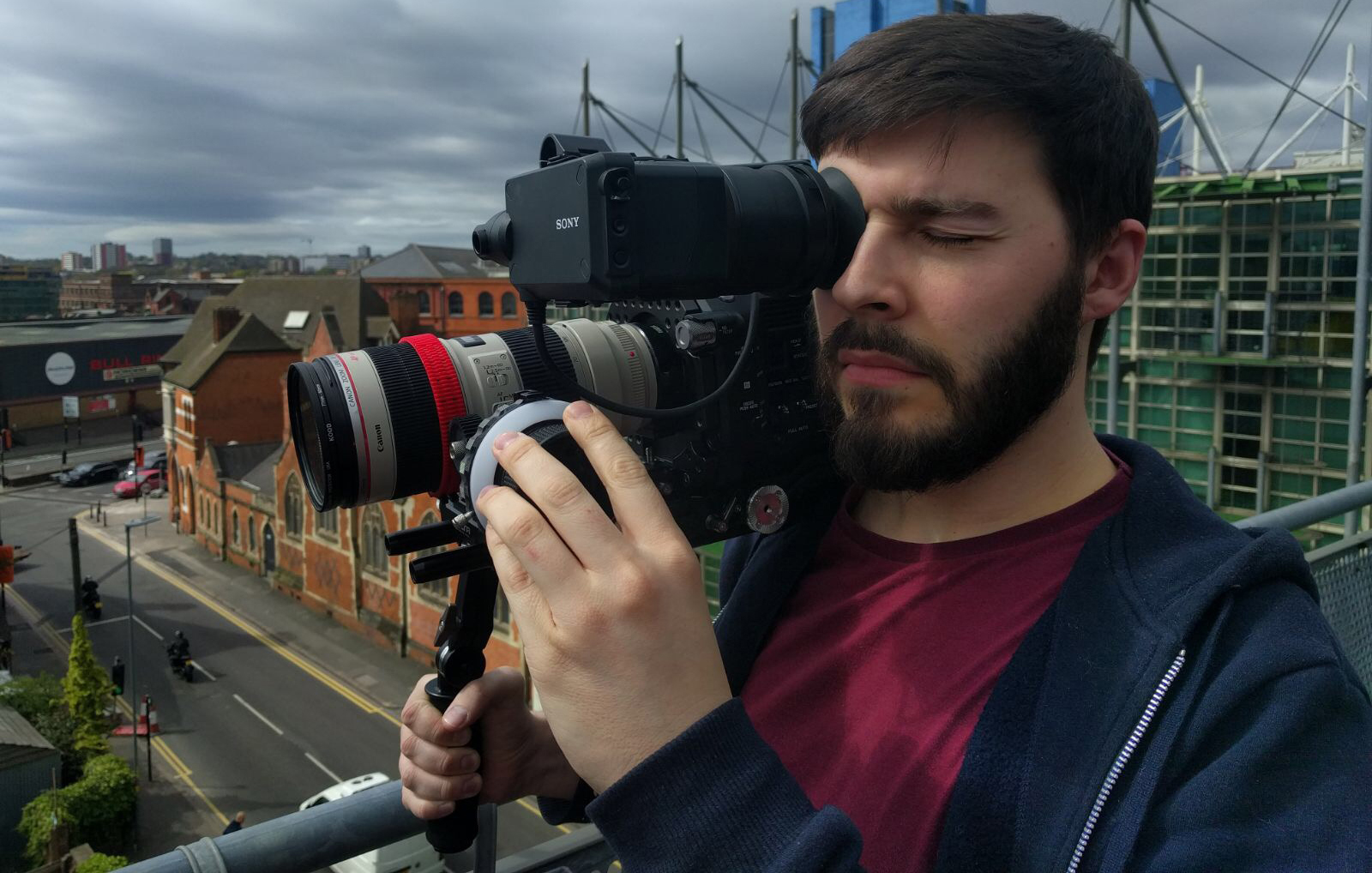 Professional Videographer operating a Sony FS7 ENG Camera against a city skyline.